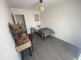 Un dormitorio pequeño y moderno con cama, mesita de noche, lámpara y un adorno en la pared.