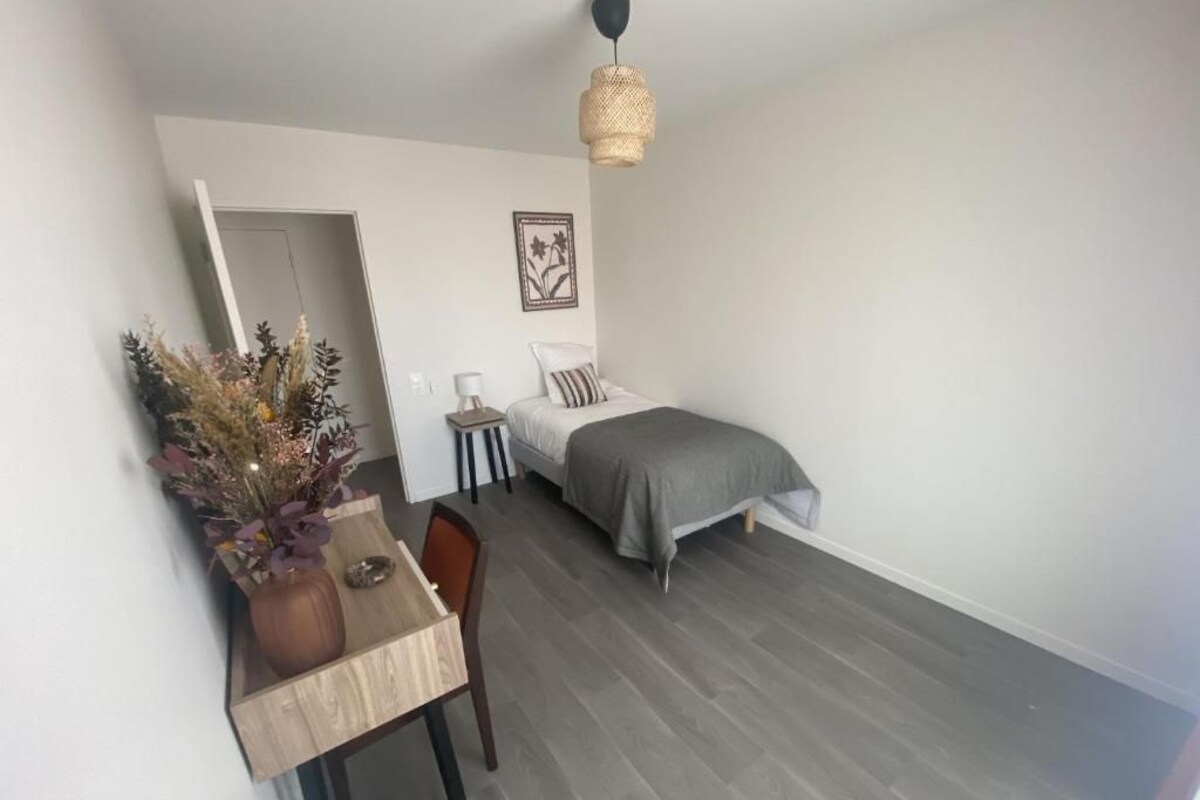 Ein gemütliches Schlafzimmer mit Bett, Nachttisch, Lampe und einer dekorativen Vase.