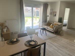 A modern living room with a dining table set for two, a sofa, and a view of the outdoors. - DOMITYS - Villa Molinis (Moulins)