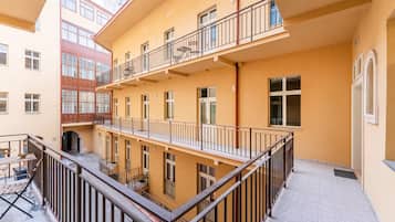 A multi-story building with balconies, a covered outdoor seating area, and a tiled ground floor.
