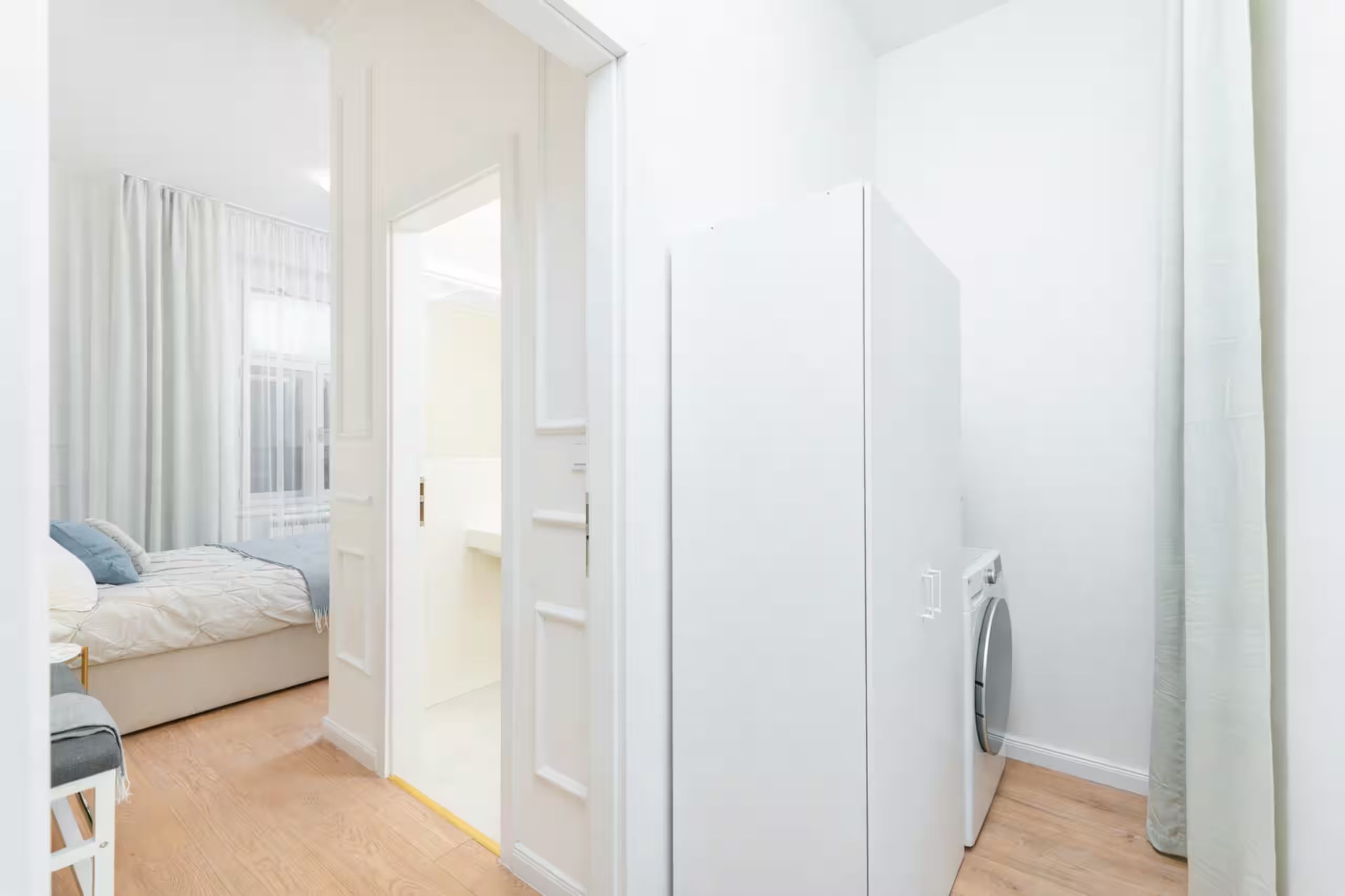 Ein Schlafzimmer mit einem Bett, einem weißen Schrank und einer Waschmaschine.