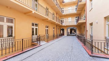 A multi-story building with balconies, a cobblestone street, and a central archway.