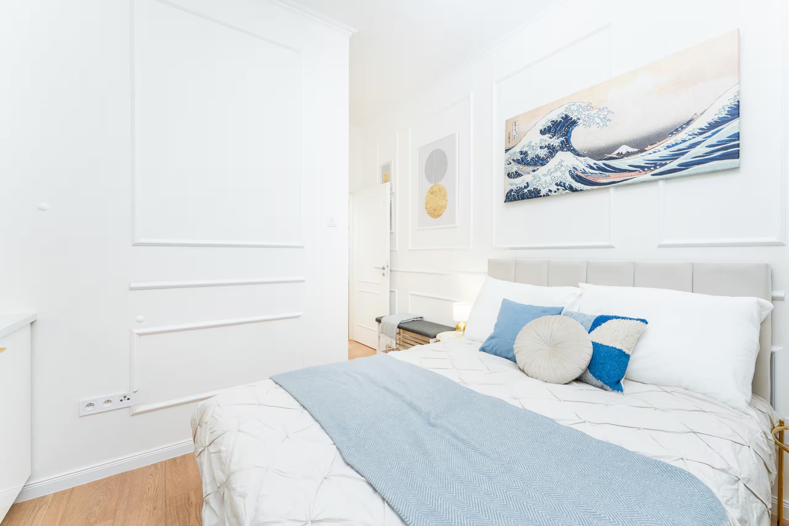 A modern bedroom with a bed, pillows, and a wall-mounted artwork.