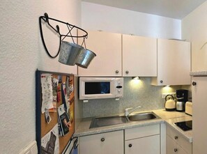 Cozinha compacta com micro-ondas, chaleira e cafeteira.