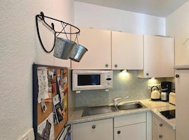 A compact kitchen with a microwave, kettle, and coffee maker.