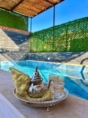 Un vassoio con teiera e bicchieri in zona piscina, con vista diretta sulla piscina.