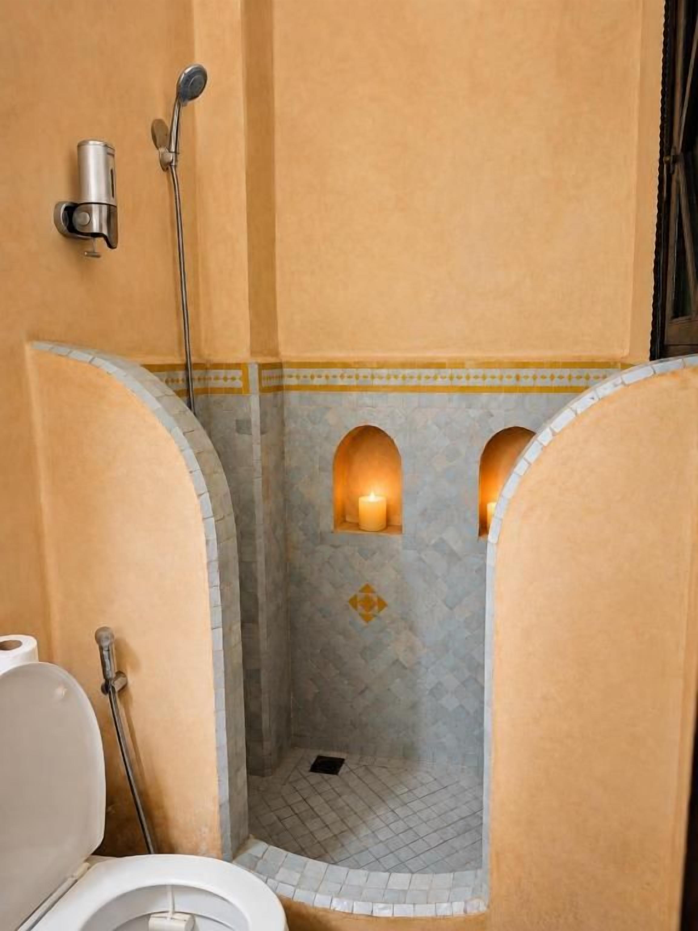 Ein Badezimmer mit Dusche, Toilette und Wandspender für Handtücher.