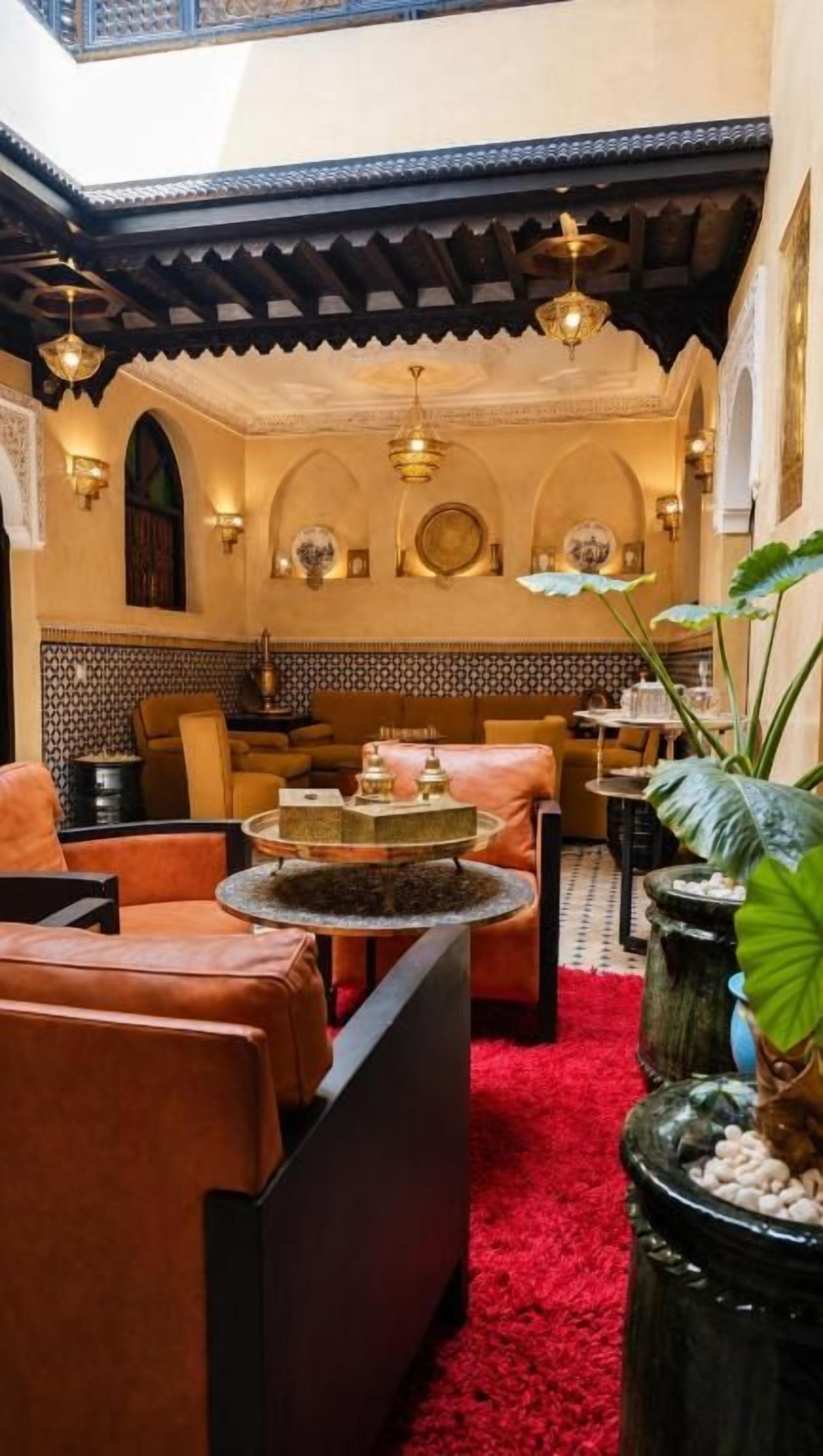 A Moroccan-style interior with leather sofas, a red carpet, and traditional decor.