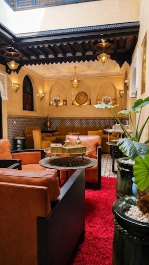 Un interno in stile marocchino con divani in pelle, un tappeto rosso e decorazioni tradizionali.