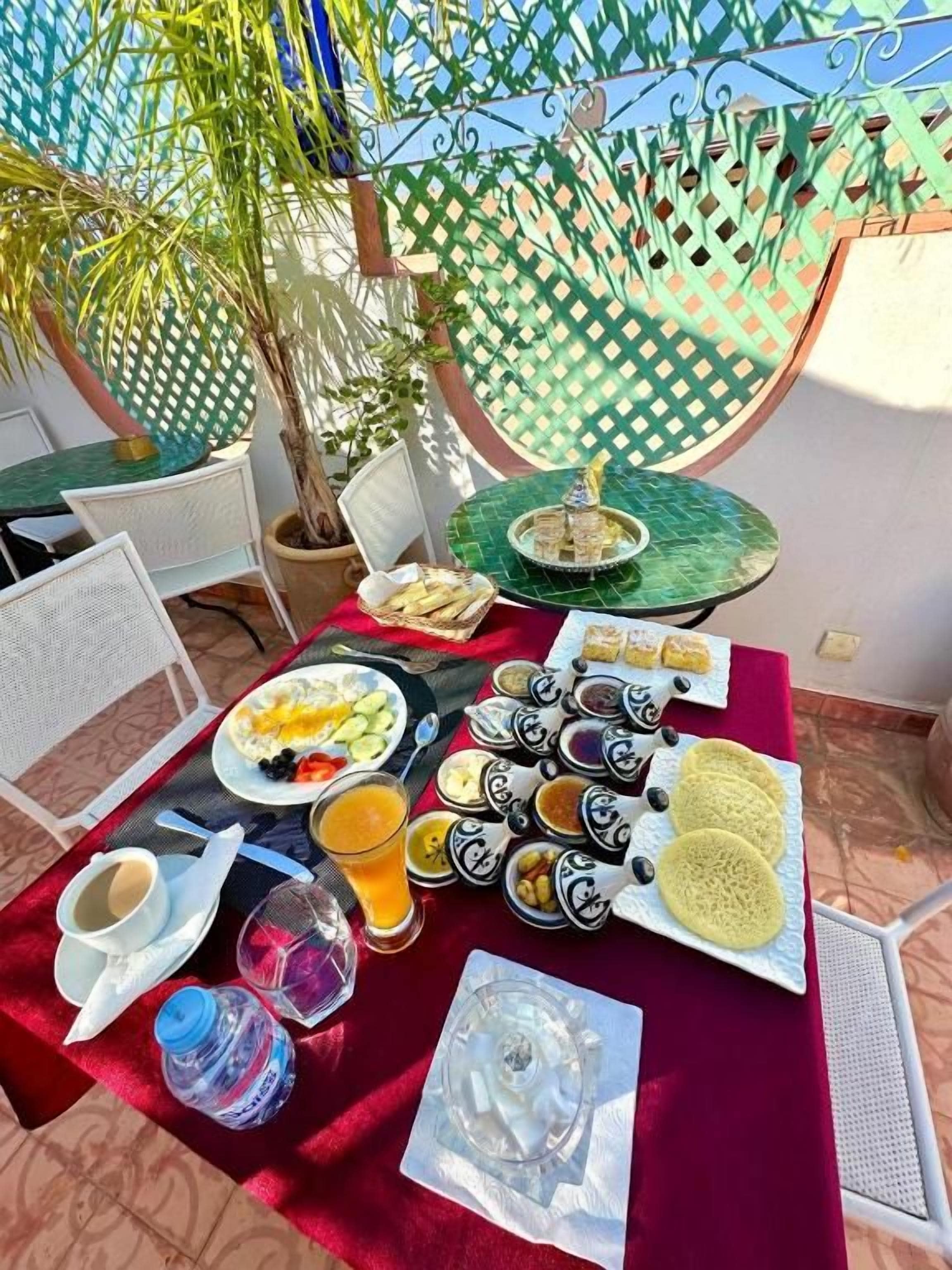 An outdoor dining area with a table set for breakfast, including plates of food, drinks, and a decorative centerpiece.