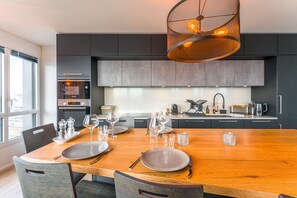 Een moderne keuken met een houten eettafel voor zes personen, voorzien van borden, glazen en bestek.