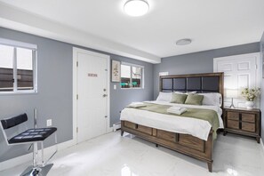 Un dormitorio con cama, mesitas de noche, una silla y una puerta con un letrero que dice 'NO ABRIR'.