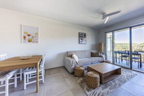 A modern living room with a dining area, a sofa, a coffee table, and a large window with a view. - Masade - cocon avec piscine partagée (Trans-en-Provence)