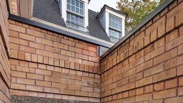 A white door with a window, a brick wall, and a concrete staircase.