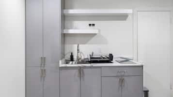 A modern kitchen with a built-in dishwasher, a countertop with a sink, and a white shelf above the sink.