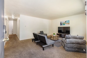 A living room with a sofa, a television, and a coffee table. - Family-Friendly 2BR Home in Lynnwood w/ Parking (Lynnwood)