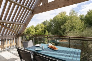A balcony with a table set for two, overlooking a forested area. - Loft au Vert – 92 m², balcon & proche plages (Saint-Lunaire)