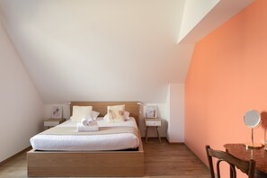 A neatly made bed with white linens and a wooden headboard in a room with an orange accent wall. - Loft au Vert – 92 m², balcon & proche plages (Saint-Lunaire)
