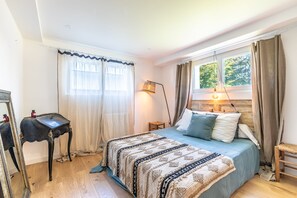A bedroom with a bed, a bedside lamp, a mirror, and a window with curtains. - Villa Gabrielle - rez-de-jardin, piscine privée (Bassussarry)