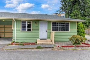 A single-story house with a green exterior, a white front door, and a garage. - Relaxing Lynnwood Getaway | Two Beds with Parking (Lynnwood)