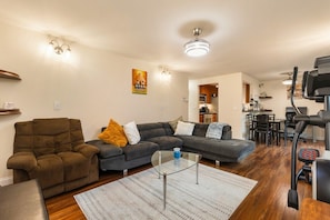 Ein Wohnzimmer mit einer Couch, einem Glastisch und einem Laufband.