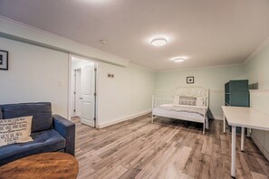 A room with a bed, a sofa, a table, and a door leading to another room.