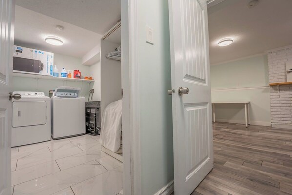 A laundry room with a washing machine, dryer, and ironing board.