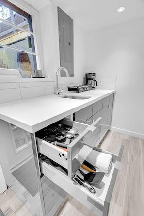 A modern kitchen with a built-in oven, a coffee maker, and a window with a view of the outside. - Modern & Minimalist 2-Bed Suite Near UBC (Vancouver)