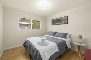 A bedroom with a bed, a window, a painting, and a small table. - Cozy 3BR Broadview Retreat | Near Transit & Parks (Seattle)