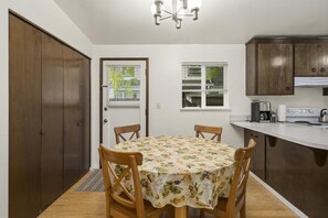 A compact kitchen with a dining table, wooden chairs, and a built-in oven. - Cozy 3BR Broadview Retreat | Near Transit & Parks (Seattle)
