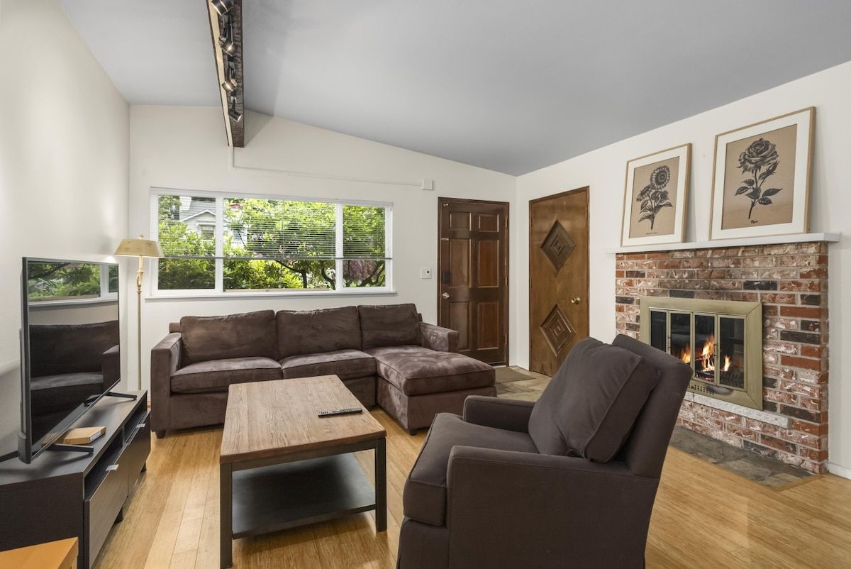 A modern living room with a sectional sofa, a coffee table, a TV, and a fireplace.