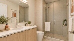 A modern bathroom with a glass shower enclosure, a sink with a mirror, and a toilet. - Toronto Five Eight Suites (Toronto)
