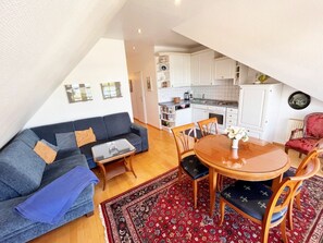 A compact living space with a sofa, a dining table, and a kitchen area. - Holiday Apartments With Baltic Sea View (Heringsdorf)