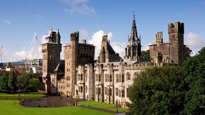 Een historisch kasteel met meerdere torens, een centrale spil en een verzorgd gazon.