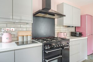 A kitchen with a gas stove, oven, and a pink refrigerator. - Cardiff Bay Victorian House Garden Sleeps 5 (Cardiff)