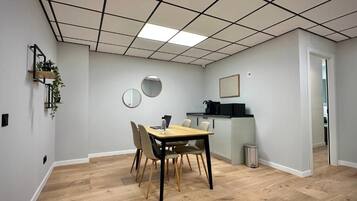 Une pièce comprenant une table à manger, des chaises, un petit coin cuisine et une poubelle.