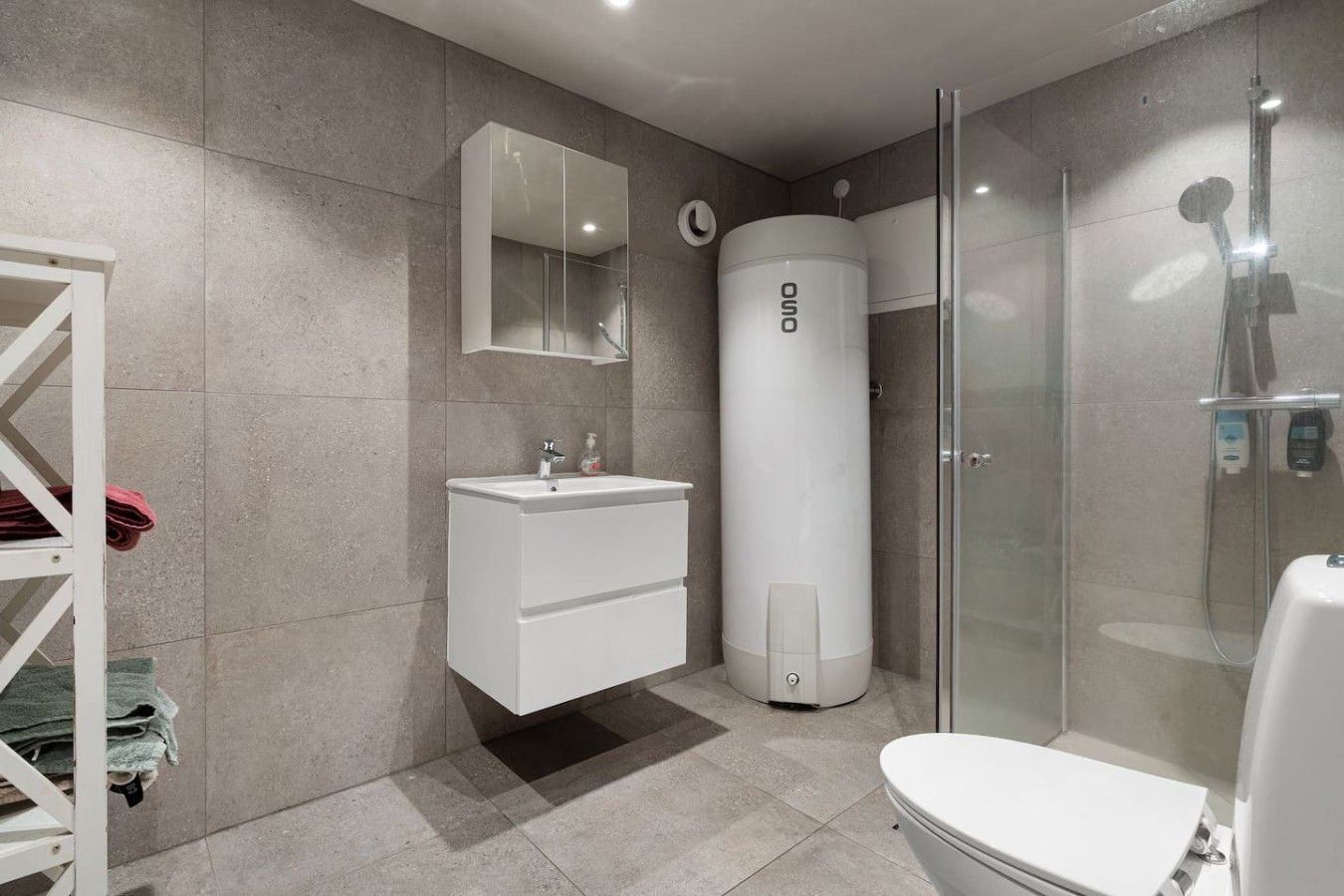 Une salle de bain moderne avec une douche à parois de verre, un lavabo blanc et des toilettes.