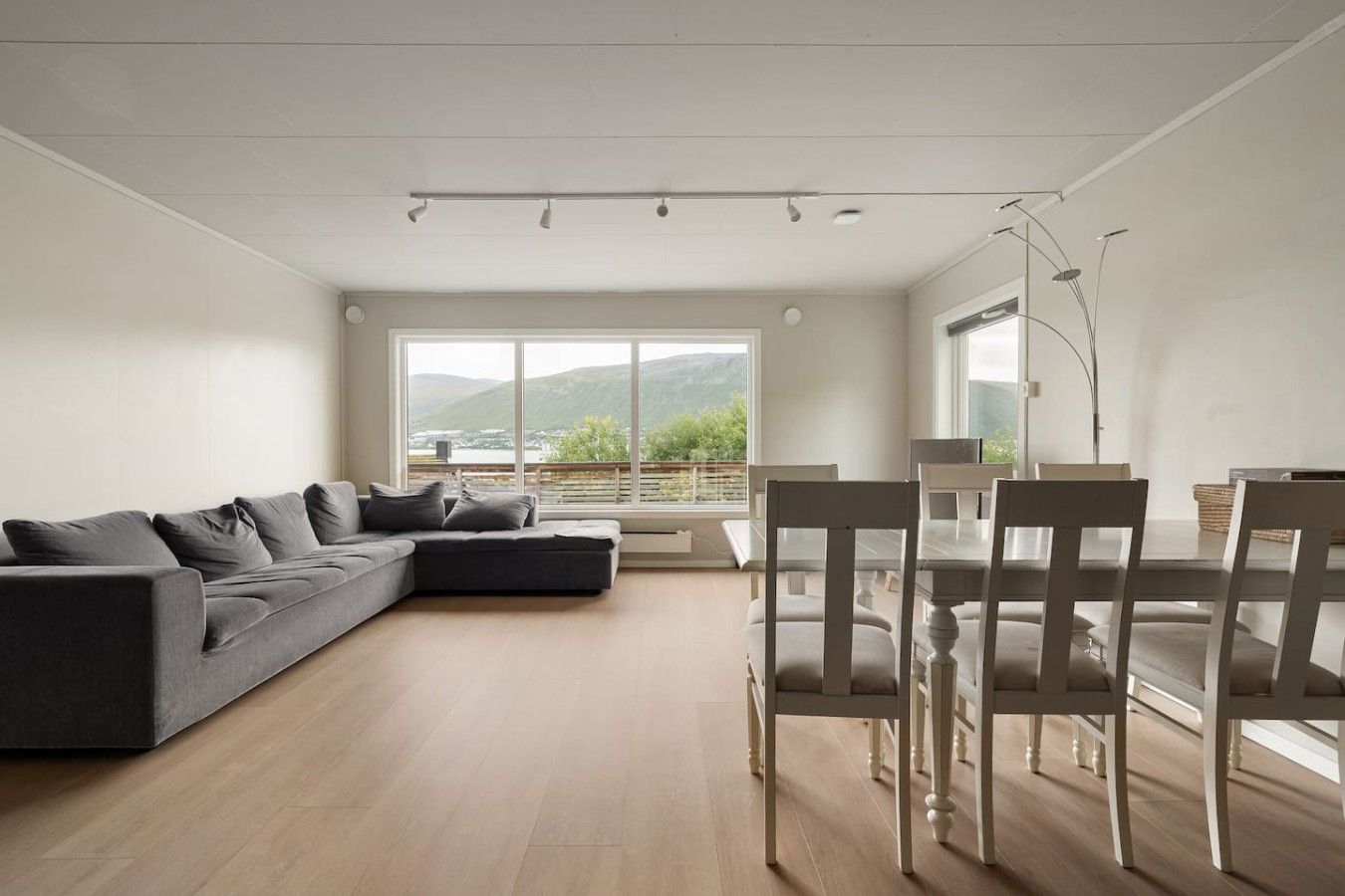 A modern living room with a sectional sofa, dining table, and chairs.