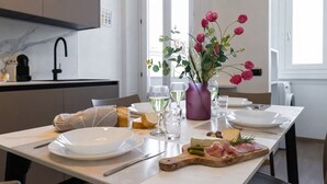 A dining table set with plates, glasses, a vase with flowers, and a wooden board with cheese and meats. - Italianway Comfort - Tunisia 22 (Milan)