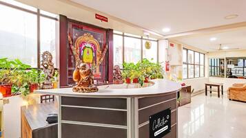 A reception area with a reception desk, potted plants, and a large religious statue.