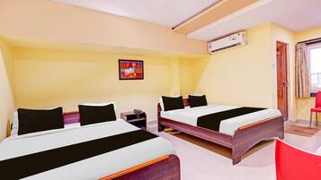 A hotel room with two beds, a painting on the wall, an air conditioning unit, and a window with curtains.