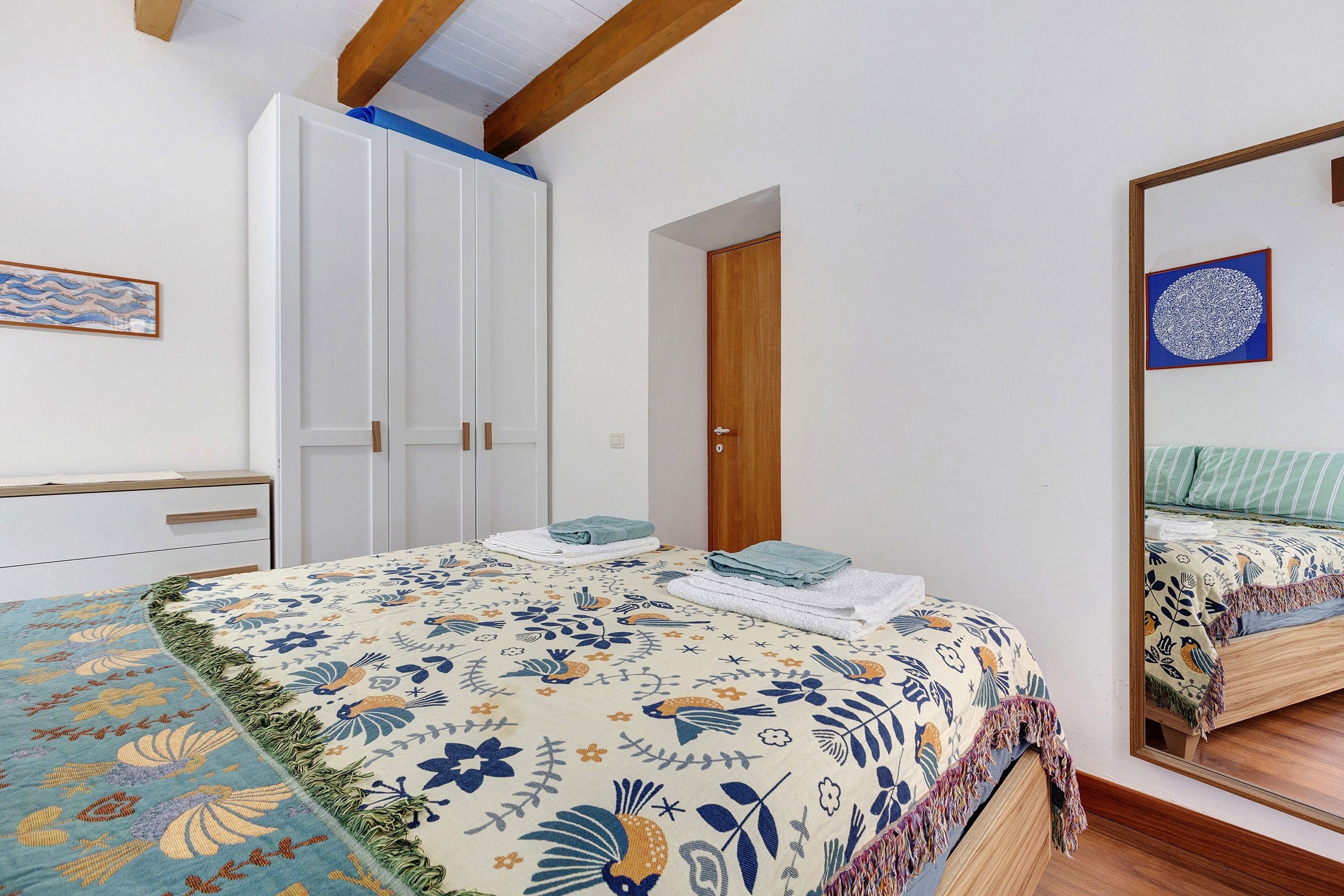 A bedroom with a bed, a wardrobe, a door, and a mirror.