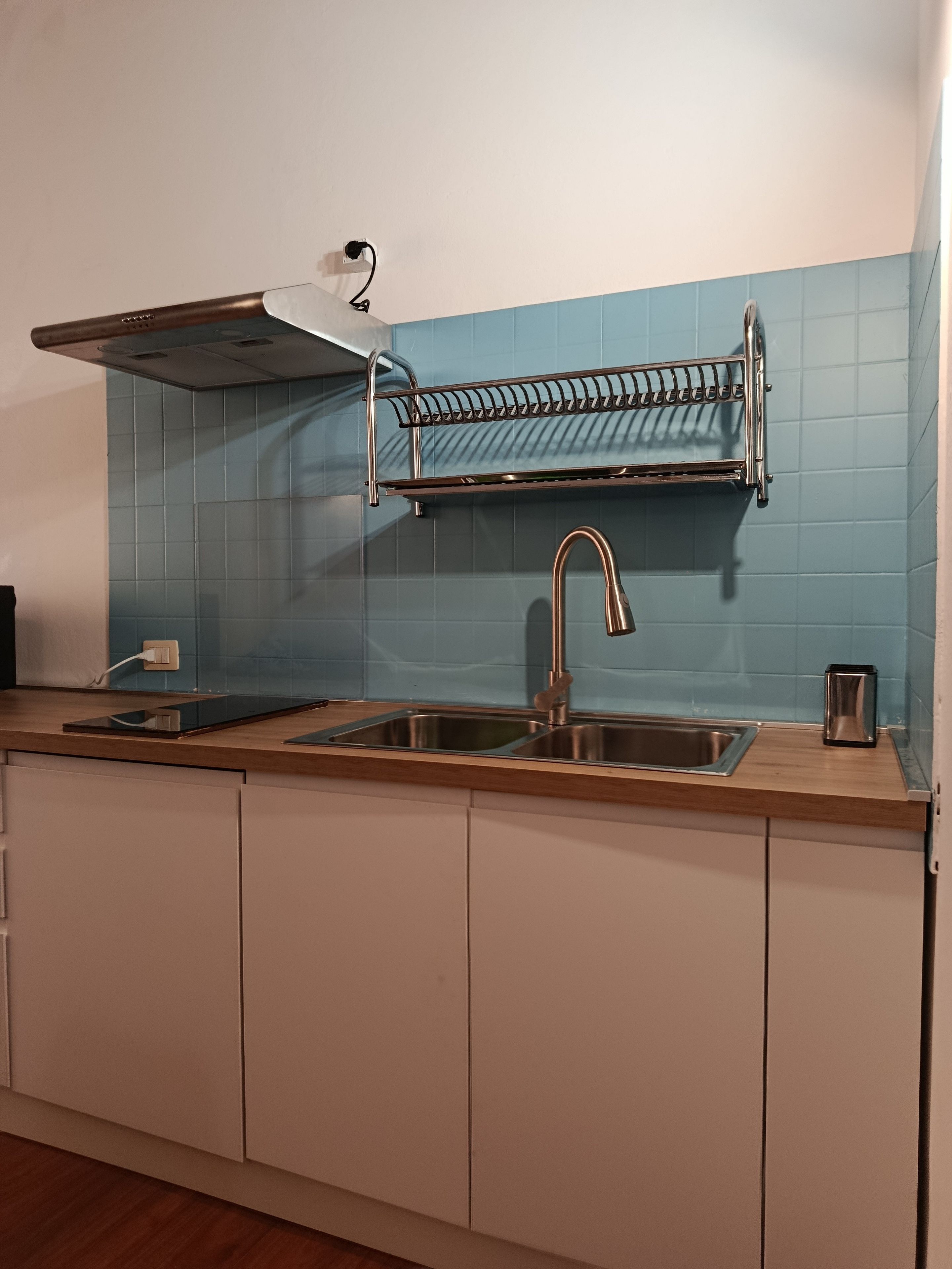 Een keuken met een dubbele spoelbak, een roestvrijstalen afzuigkap, een afwasschuurrek en een broodrooster.