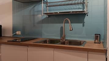 Een keuken met een dubbele spoelbak, een roestvrijstalen afzuigkap, een afwasschuurrek en een broodrooster.