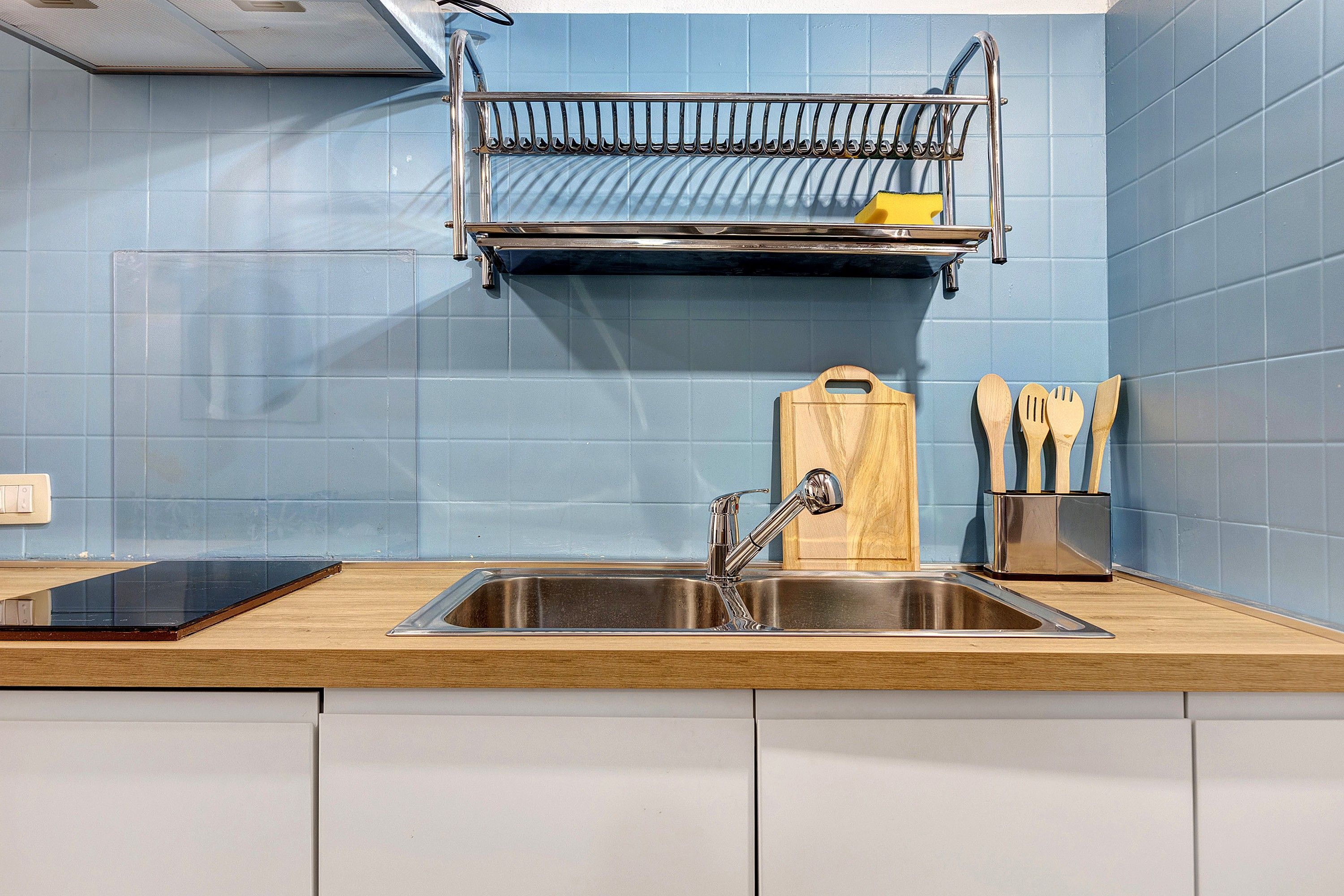 Una cucina con lavello in acciaio inossidabile, piano di lavoro in legno e scolapiatti sopra.