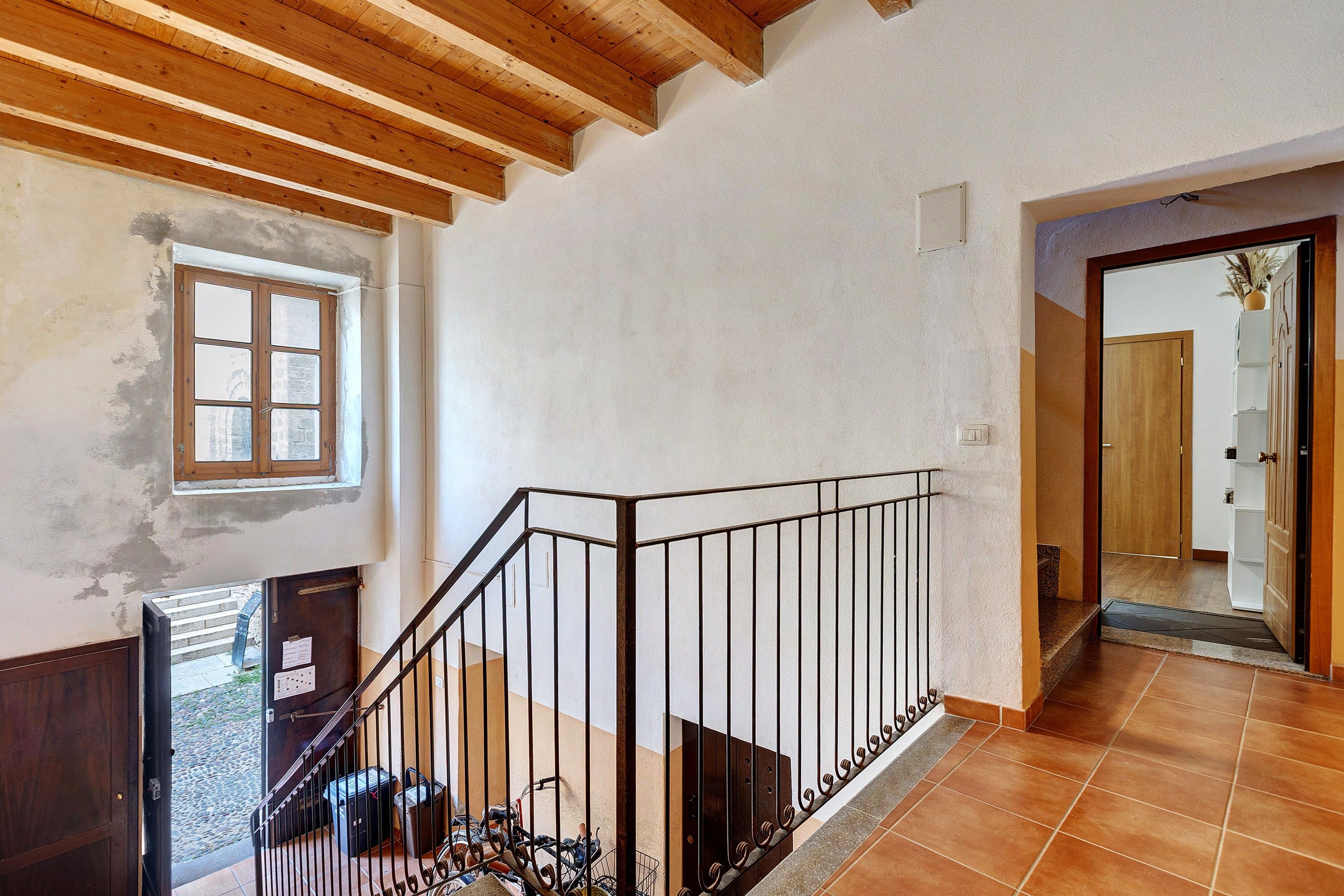 A staircase with a metal railing, a wooden door, and a window with a view of the outside.