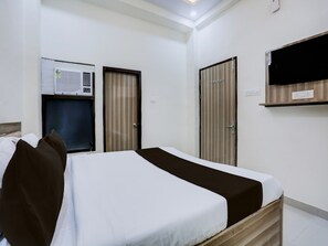 Una habitación de hotel con cama, armario, espejo y aire acondicionado.