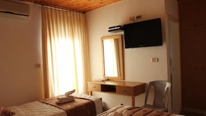 Quarto de hotel com duas camas, teto de madeira, televisão de tela plana, espelho e escrivaninha com cadeira.