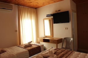 Habitación de hotel con dos camas, techo de madera, televisor de pantalla plana, espejo y escritorio con silla.