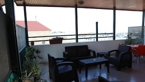 Uma área de estar coberta ao ar livre com vista para a cidade, equipada com cadeiras e mesas.